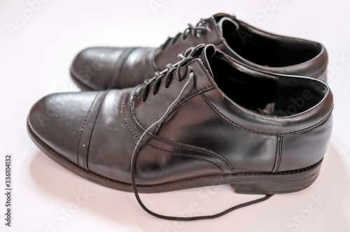 Close up of well worn classic black leather men's shoes on a plain white background with selective focus