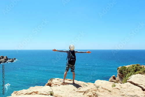 Man traveler with backpack hold rise hands at sea water. Travel and wanderlust concept. Summer vacation and adventures. Young man is going to marine trip.Life and freedom concept. Malta