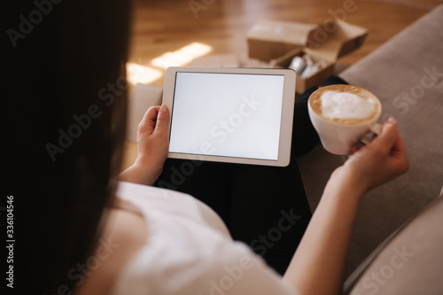 Woman shopping online at home use tablet. Woman work on tablet and drink cappuccino. Quarantine time. Boxes on the floor. Parcel