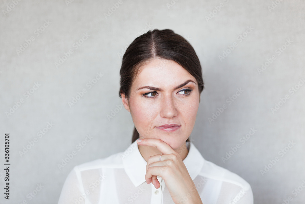 Closeup portrait of pretty mad young woman, finger on lips, daydreaming something serious and upsetting. Human facial expressions, emotions, feelings, signs, symbols Closeup portrait of pretty mad young woman, finger on lips, daydreaming something serious and upsetting. Human facial expressions, emotions, feelings, signs, symbols