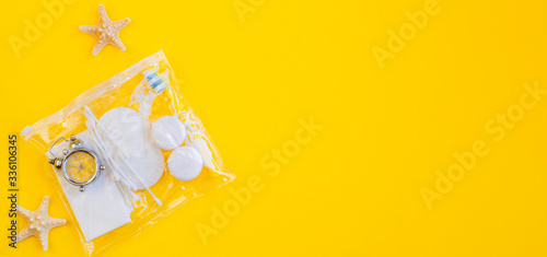 Plastic packaging. Rides set on a yellow background. Plastic bottles, watches, toothbrushes, containers for lenses and dental floss in a sealed bag. Going on vacation.top view, copy space