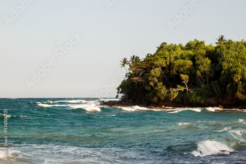 untouched tropical beach with rocks in the water and white waves in Sri Lanka