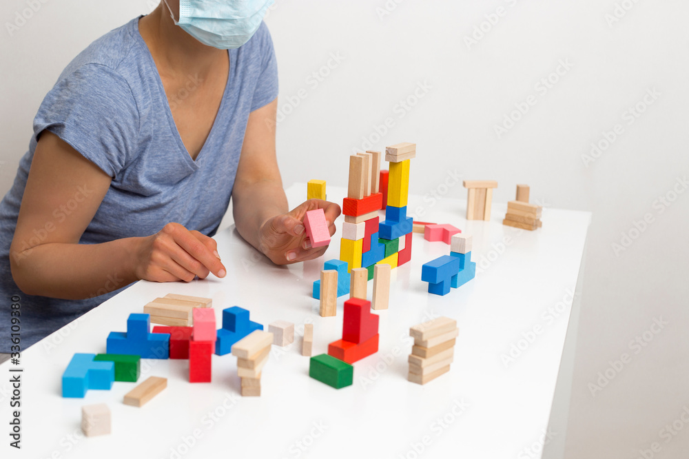 A woman in a medical mask plays dice at home. Quarantine concept. A woman in a medical mask plays dice at home. Quarantine concept.