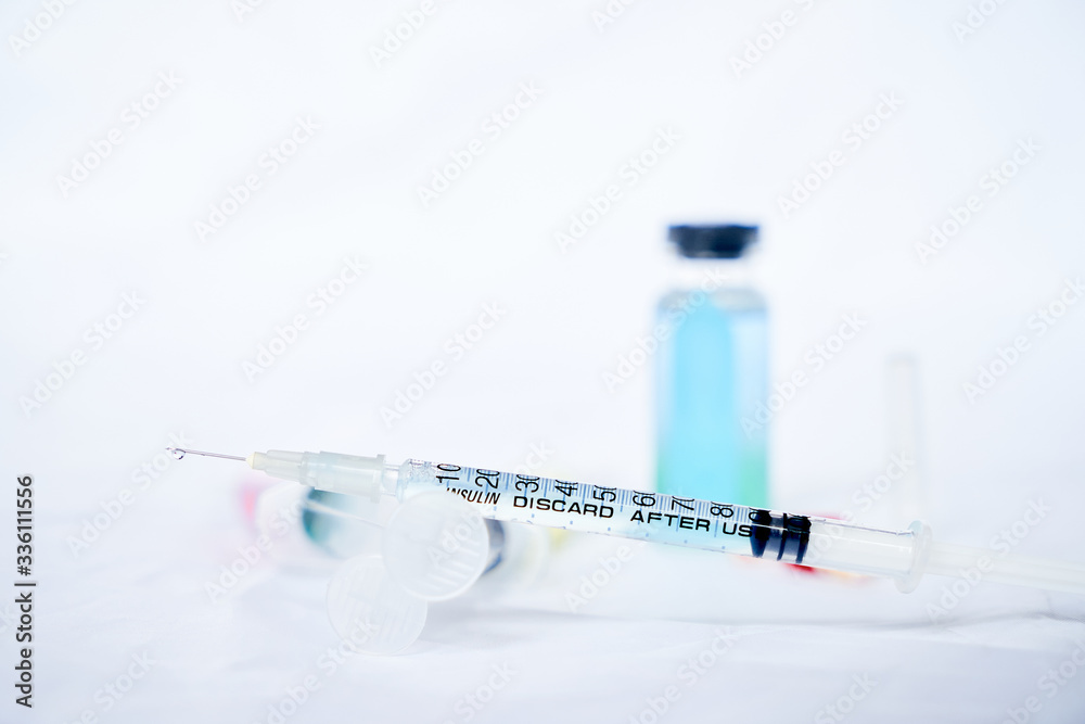 A syringe for injection with a coronavirus vaccine, antiviral tablets and 2 syringes with red and yellow liquids on a white background A syringe for injection with a coronavirus vaccine, antiviral tablets and 2 syringes with red and yellow liquids on a white background