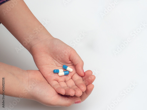 woman's hand holding blue and white tablets. self-medication during coronavirus