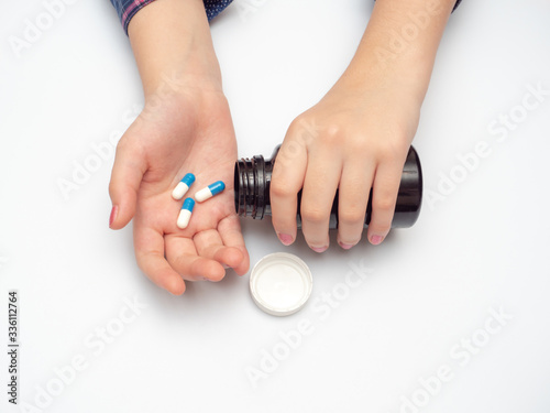 woman's hand holding blue and white tablets. self-medication during coronavirus