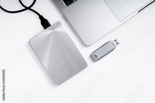 Portable hdd connected to a laptop and a usb flash drive on a grey background  flat lay. Data storage concept