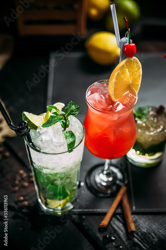 Variety of sweet alcohol coktails in different glasses, mojito, mai tai and sex on the beach, side view, vertical photo