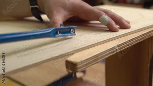 Wallpaper Mural person hands cut brown wooden plywood with jigsaw on special support creating old jetliner model extreme close view Torontodigital.ca