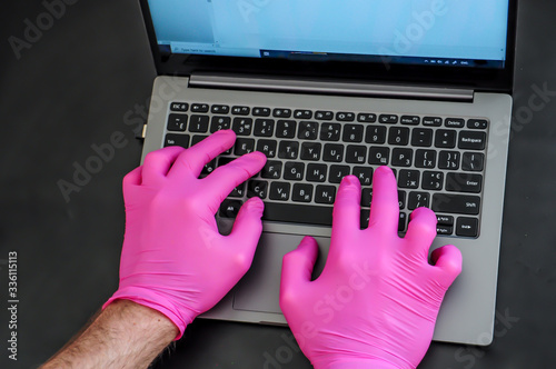 Man hand typing in sanitary gloves. Quaratine work. photo