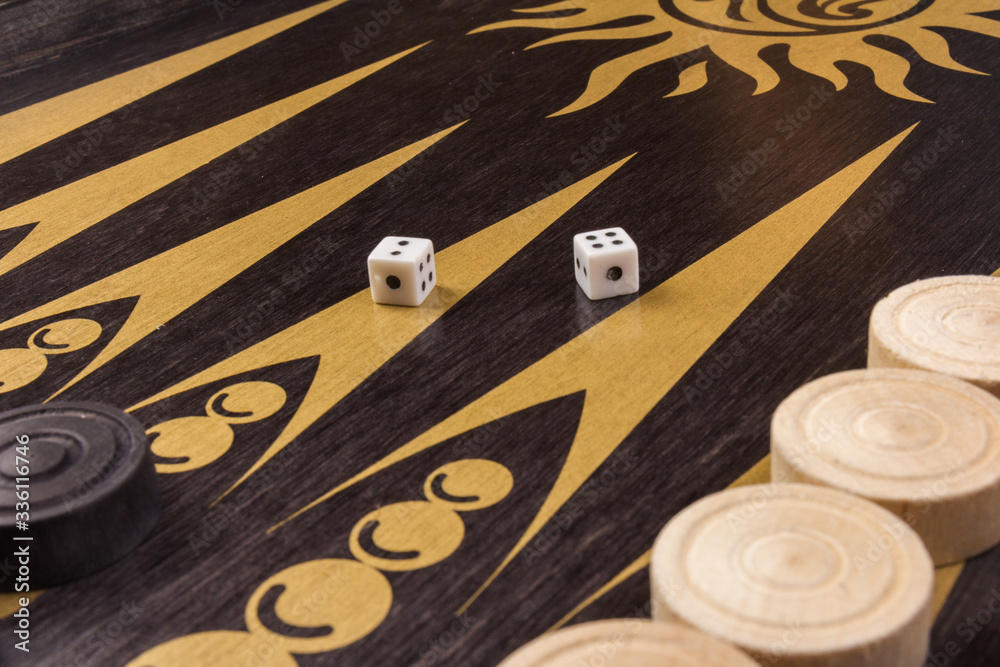 Obraz premium Backgammon. Board game. White cubes and chips on a blackboard. Dice on backgammon board game. Selective focus. Playing leisure games