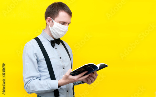 side view of handsome man in white medical face mask readind blue usa constitution and independence declaration in front of yellow background with copy space photo