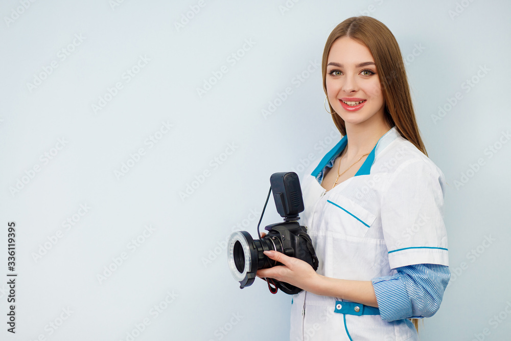 Image of a woman doctor isolated over white wall background. Dentist with a camera in hand. Copy space. Beautiful girl in a white coat Image of a woman doctor isolated over white wall background. Dentist with a camera in hand. Copy space. Beautiful girl in a white coat