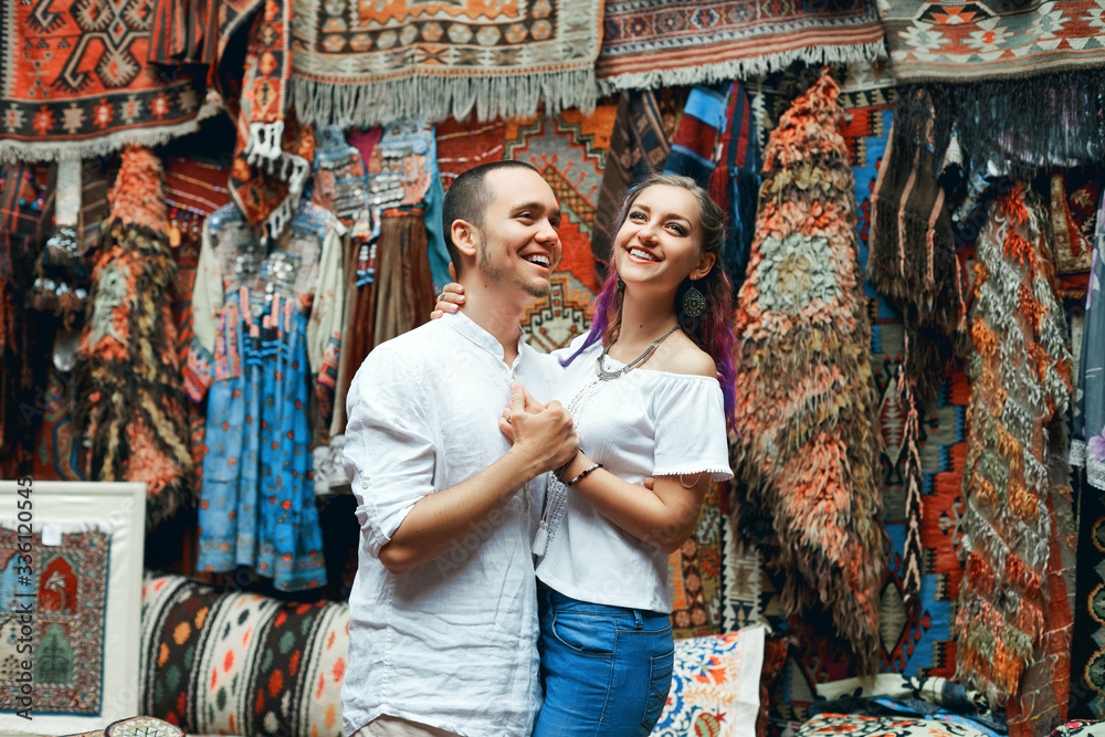 Couple in love walks and hugs at the Eastern carpet market. A man and a woman choose a Turkish carpet