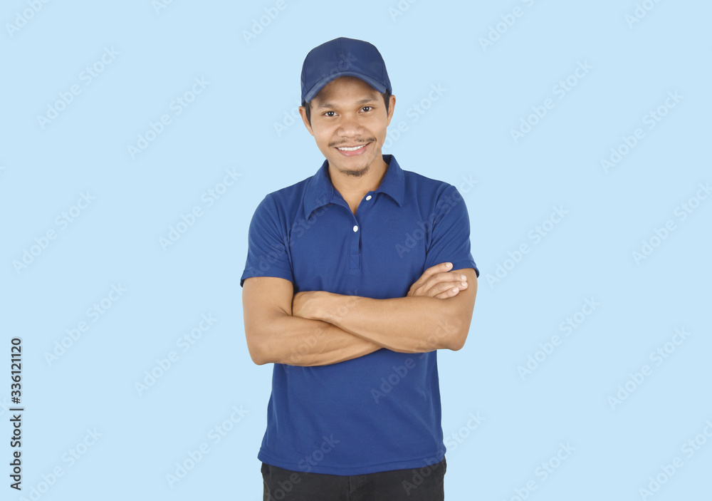Delivery service concept. Portrait delivery man standing with arms crossed on blue background. looking at camera. Delivery service concept. Portrait delivery man standing with arms crossed on blue background. looking at camera.