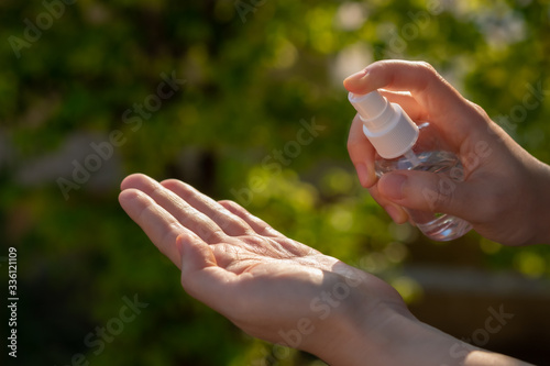 Hand of Asian woman applying the alcohol spray with greenery background. Closed up alcohol spray. Killing the virus. © tanita