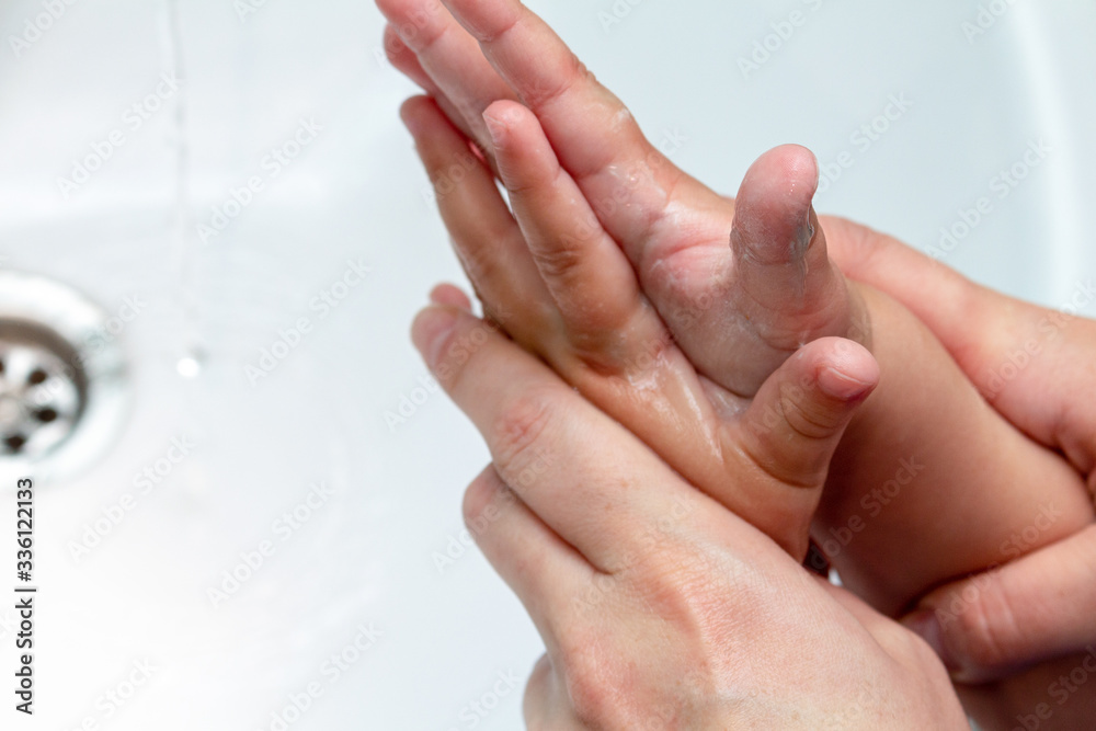 Fototapeta premium woman helps children wash hands under the tap close-up