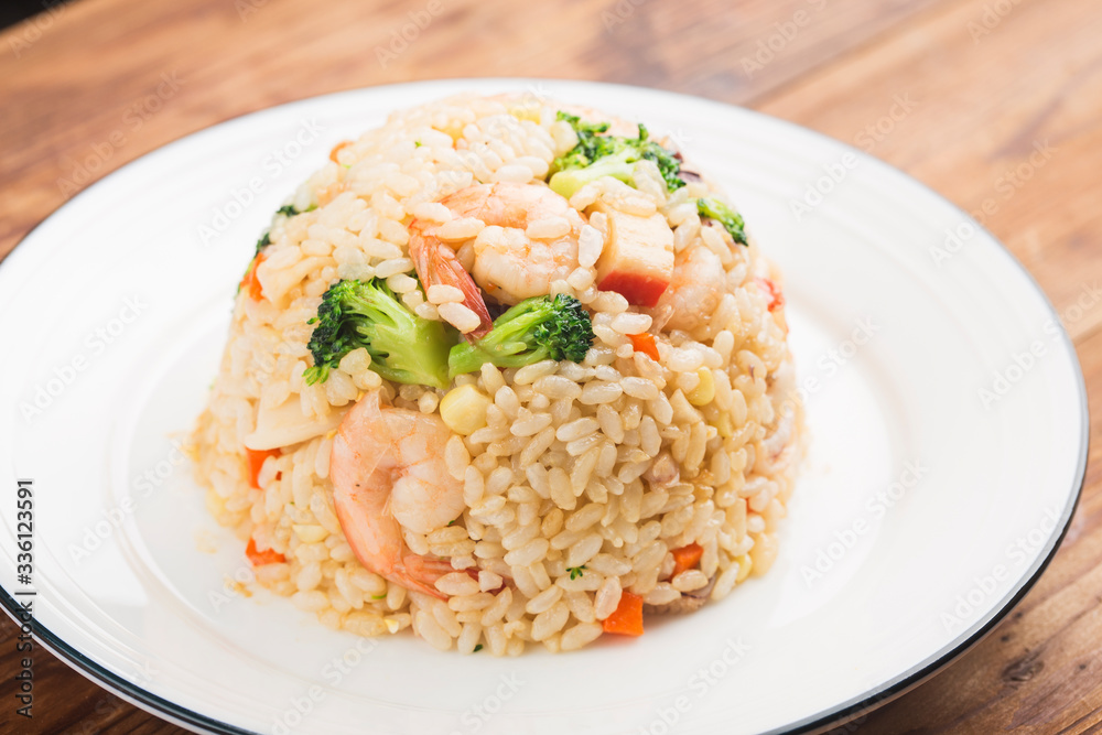 Fried rice with shrimp on the white dish on wooden table from top view Fried rice with shrimp on the white dish on wooden table from top view