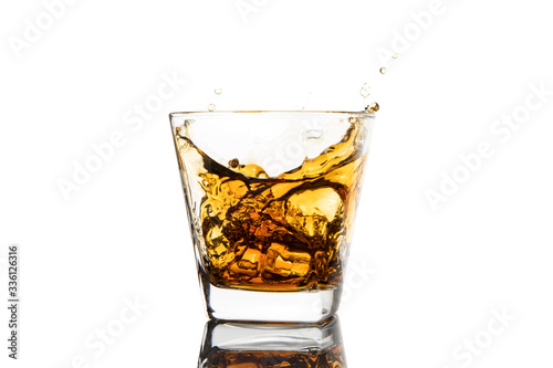 Whiskey glass with ice splashes. Glass of splashing whiskey with ice isolated on white