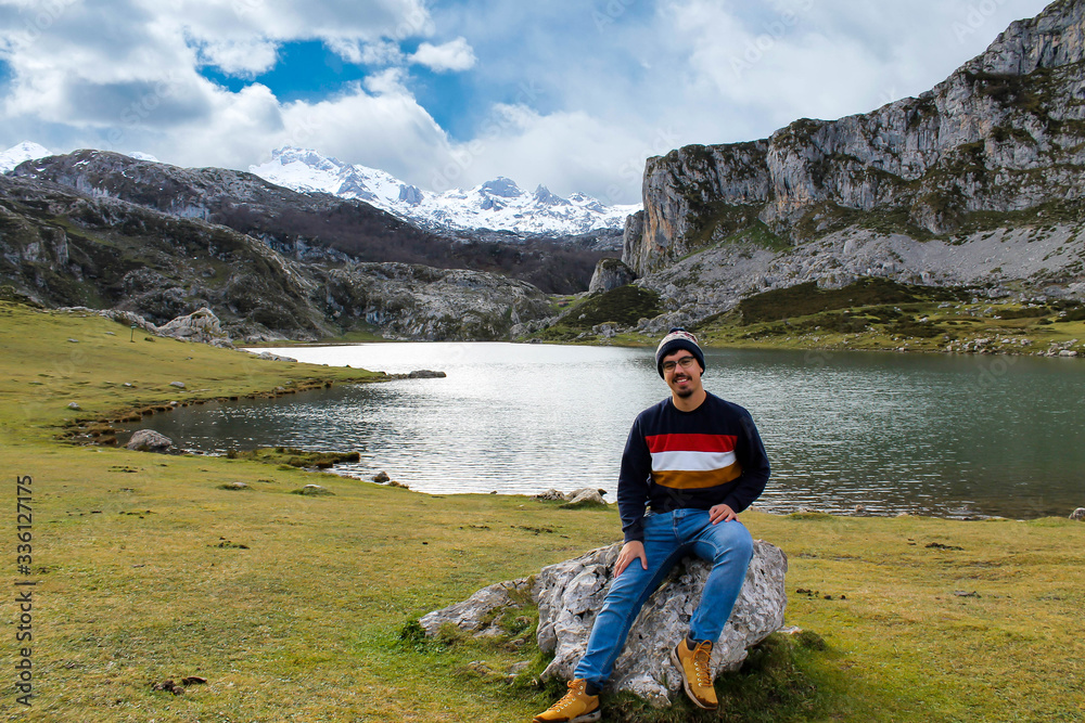 Boy sitting front on a rock, looking at the views of the lake and the mountain Boy sitting front on a rock, looking at the views of the lake and the mountain