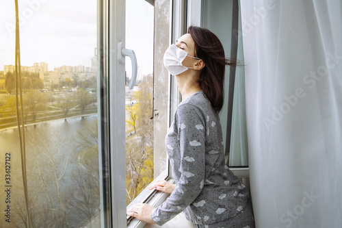 Free Download stay at home. girl looks out the window with a mask on her face - GFXLoad