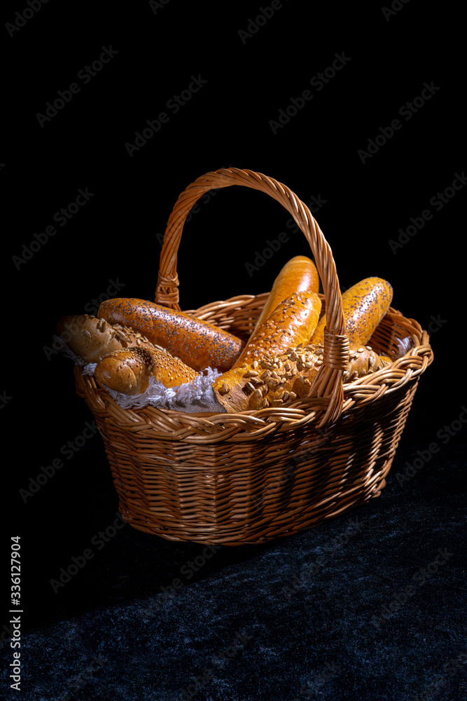 Fresh rolls in basket on dark background. Poppy seed roll and sesame seed roll. Typical popular czech breakfast rolls or buns.