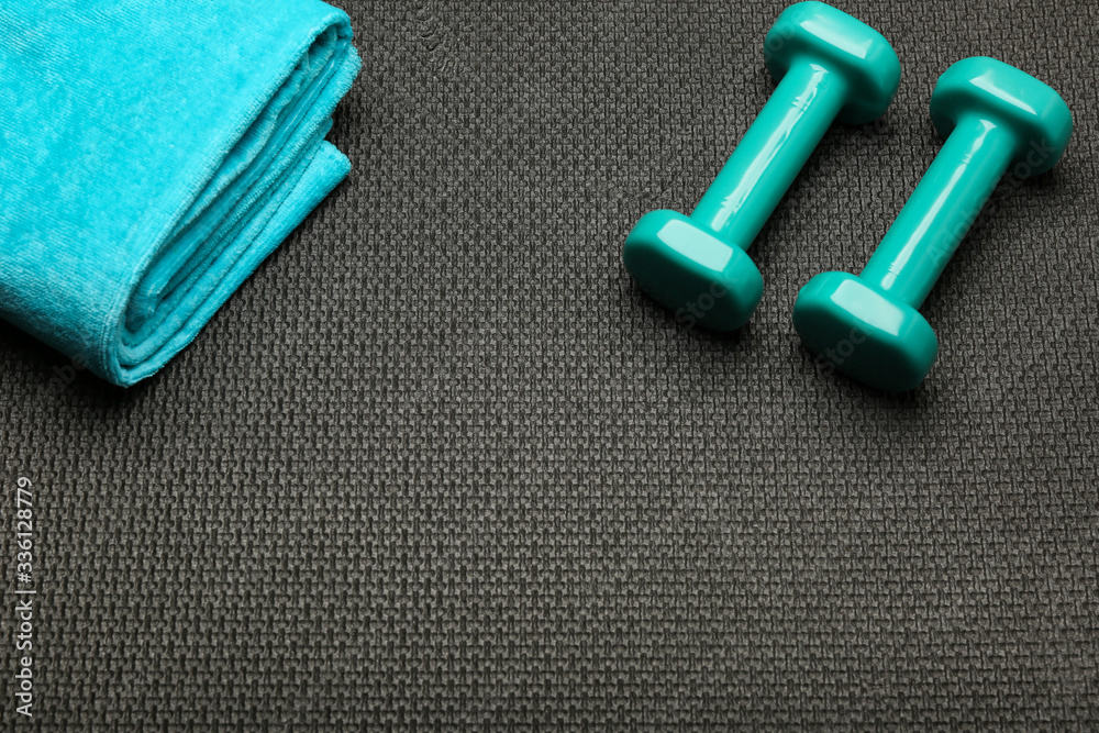 sport flat lay with turquoise dumbbells and towel on black sport mat top view sport flat lay with turquoise dumbbells and towel on black sport mat top view