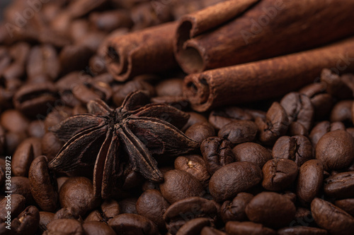 Three cinnamon sticks and a star anise against the background of coffee beans