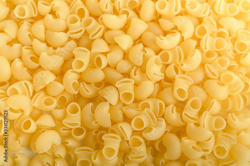 Heap of dried cornetti rigati Italian pasta isolated on a white table, top view or flat lay of healthy food 