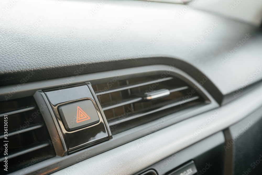 Closeup on emergency button with red triangle icon on car dashboard. The concept of a problem, stop, accident or damage.
