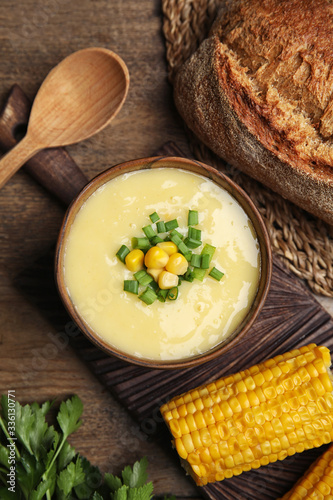 Delicious corn cream soup served on wooden table, flat lay