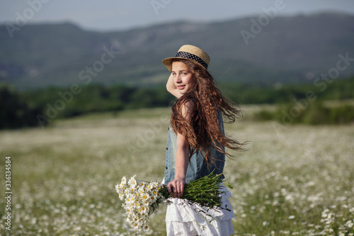 Beautiful teenage girl in a white dress and hat walking