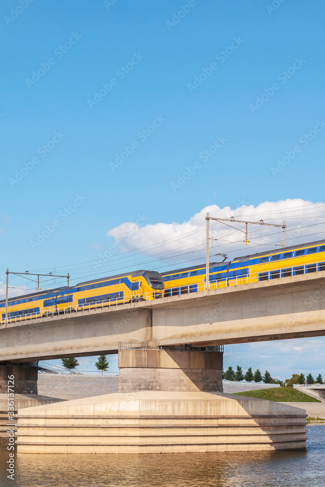 Dutch train crossing the sideskirts of the river Waal in front of the city of Nijmegen Dutch train crossing the sideskirts of the river Waal in front of the city of Nijmegen