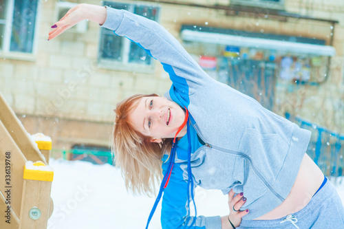 fit active young blond woman performing training and doing her warming up exercise with jumping rope outdoors snowy winter
