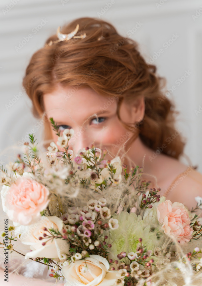 A wedding flower bouquet made of white roses and other flowers is held in her hands by a shapely redhead bride girl in defocus. A wedding flower bouquet made of white roses and other flowers is held in her hands by a shapely redhead bride girl in defocus.