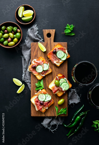 Prosciutto bites served with wine and assorted olives, top down view