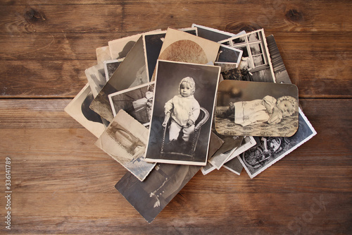 old vintage monochrome photographs in sepia color are scattered on a wooden table, the concept of genealogy, the memory of ancestors, family ties, memories of childhood
