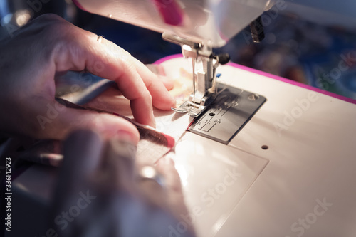 Fototapeta Naklejka Na Ścianę i Meble -  detail of the hands of a woman sewing on a machine