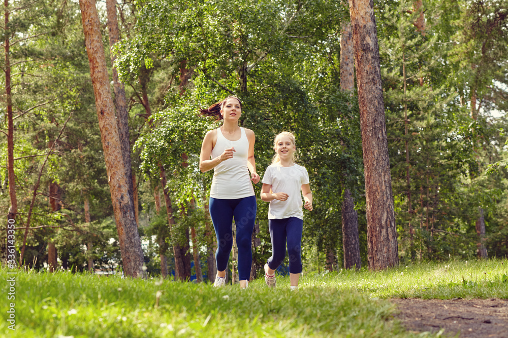 running sporty mother and daughter. woman and child jogging in a park. outdoor sports and fitness family. running sporty mother and daughter. woman and child jogging in a park. outdoor sports and fitness family.
