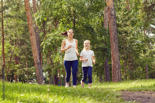 running sporty mother and daughter. woman and child jogging in a park. outdoor sports and fitness family. © bakharev