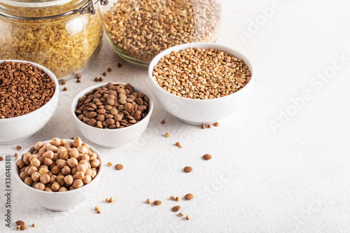 cereals buckwheat chickpeas lentils on a white table side view assorted wooden spoon