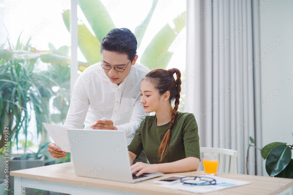 at home, a modern couple preparing their next vacation destination on a laptop, their home is modern and bright at home, a modern couple preparing their next vacation destination on a laptop, their home is modern and bright