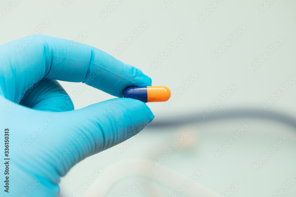 Hand in medical gloves holding capsules. Medicine pills or capsules in hand, palm or fingers of a doctor or nurse. Hand in medical gloves holding capsules. Medicine pills or capsules in hand, palm or fingers of a doctor or nurse.