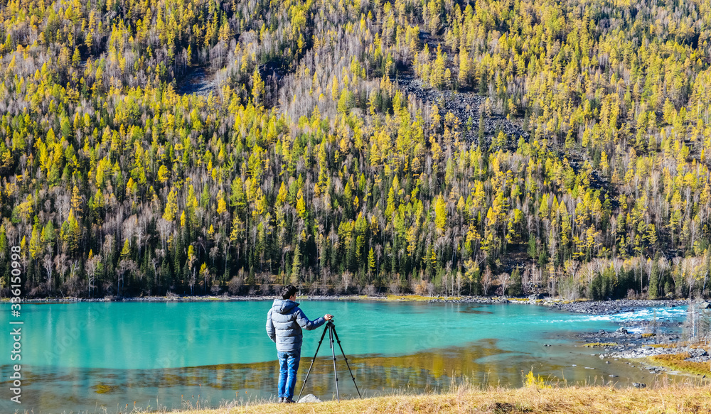 Obraz premium man enjoys peaceful view of Wolong Bay at Kanas Lake