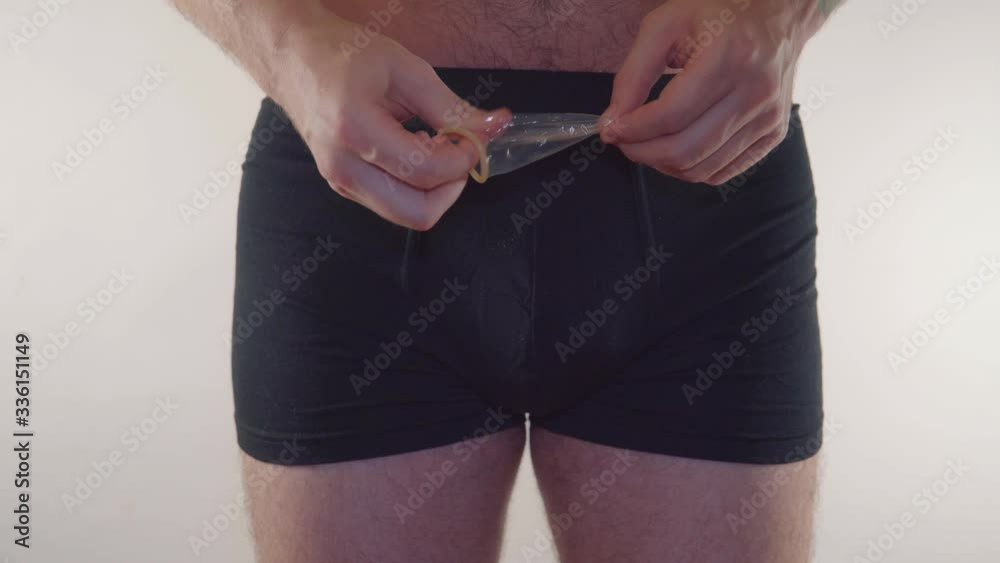 Closeup of a man in underwear holding a condom on an white background