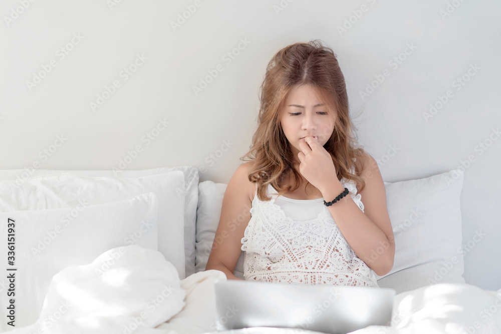 Young beautiful Asian female using laptop or notebook for working at home or shopping online while laying on bed in her bedroom. Communication Technology, marketing online, social media concept. Young beautiful Asian female using laptop or notebook for working at home or shopping online while laying on bed in her bedroom. Communication Technology, marketing online, social media concept.