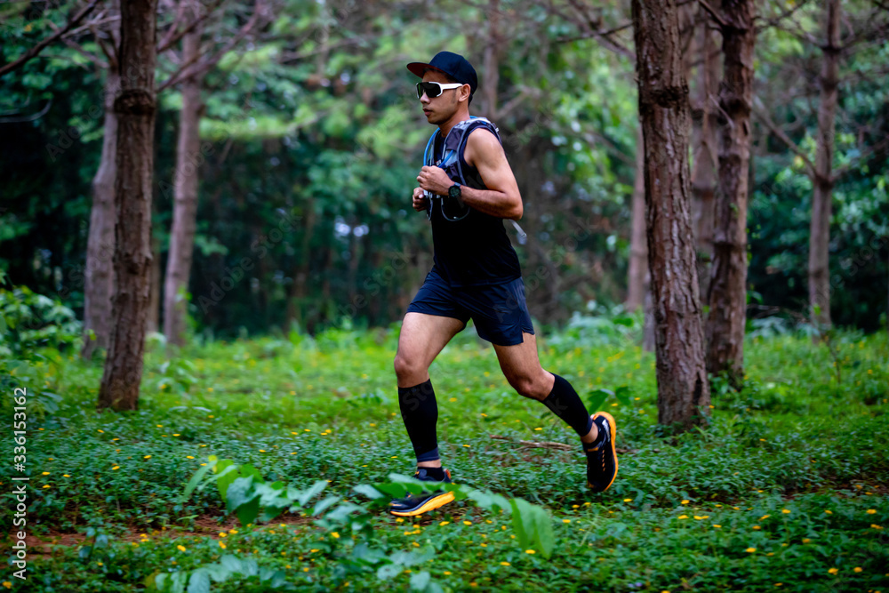 A man Runner of Trail and athlete's feet wearing sports shoes for trail running in the forest A man Runner of Trail and athlete's feet wearing sports shoes for trail running in the forest