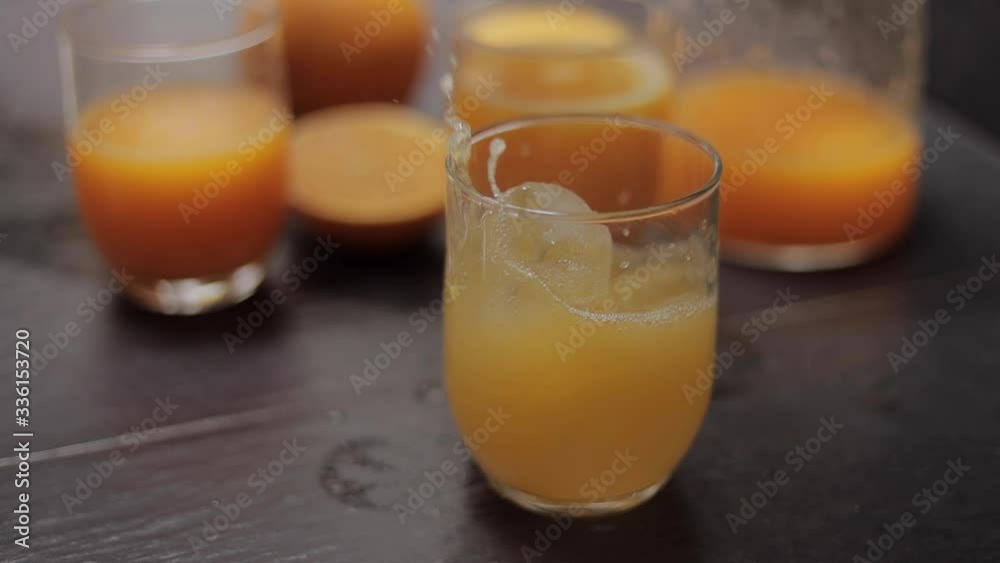 Close up ice drop in glass with orange juice. Slow motion Close up ice drop in glass with orange juice. Slow motion