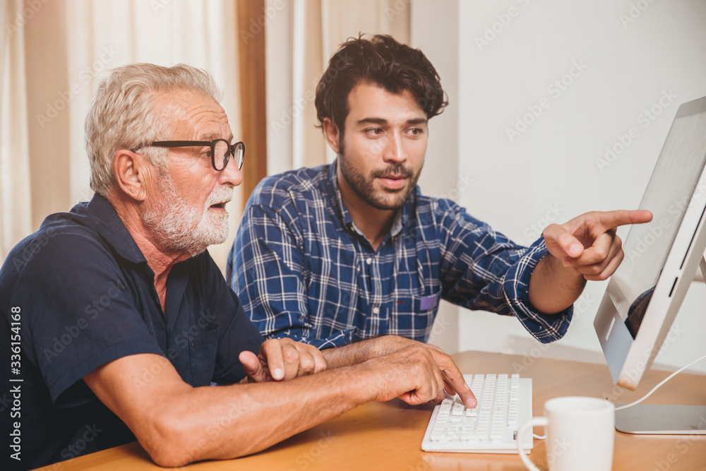 young man or son teaching his grandfather elderly dad learning to using computer at home. - obrazy, fototapety, plakaty 