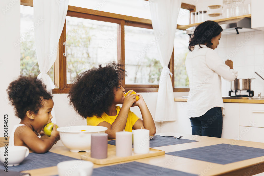 Fototapeta premium Mother cooking for her two children waiting for lunch. Single mom concept.